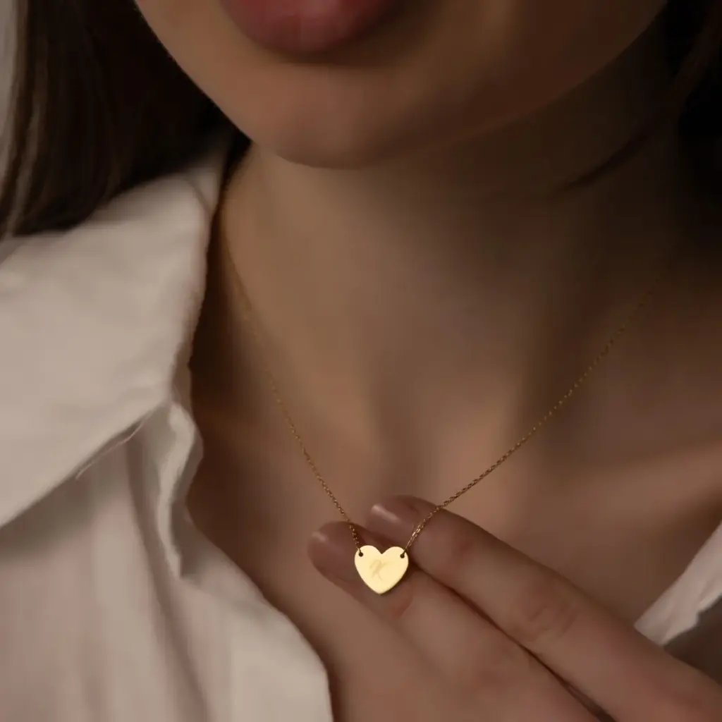 Beyaz gömlekli modelin elinde tuttuğu küçük kalp kolye